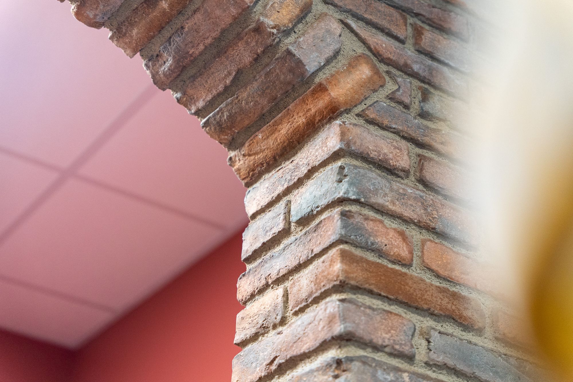 Arche en briques anciennes devant un plafond rose, Angel Carrelages