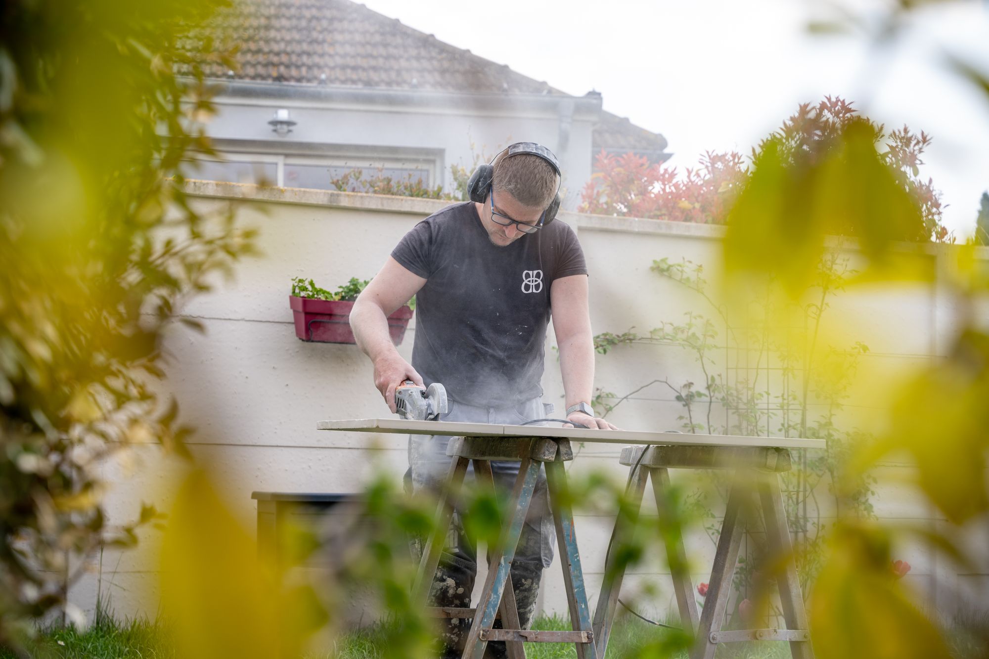 Carreleur découpant un carreau dans un jardin, Angel Carrelages