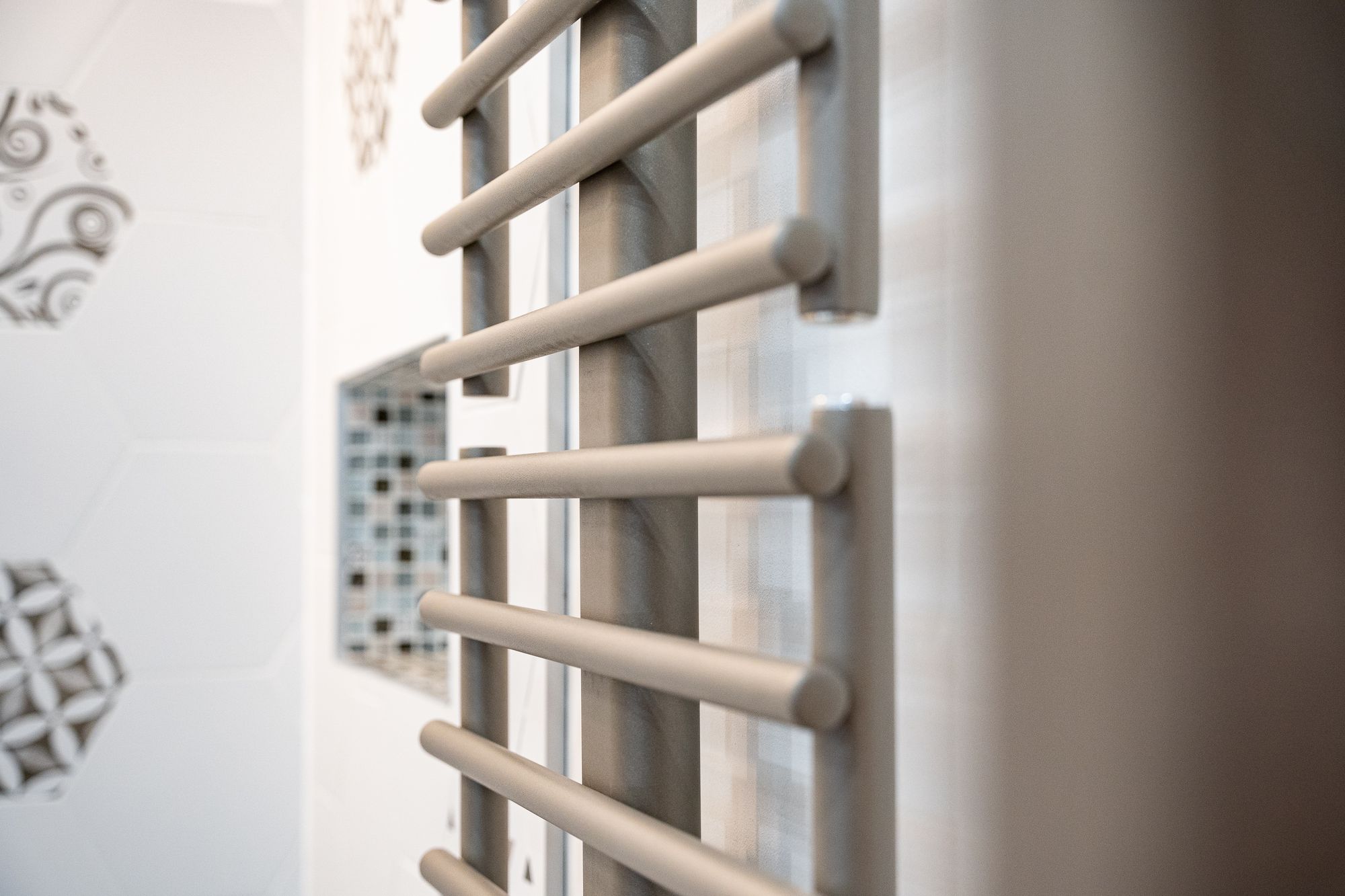 Sèche-serviettes devant un mur de carreaux à motifs, Angel Carrelages