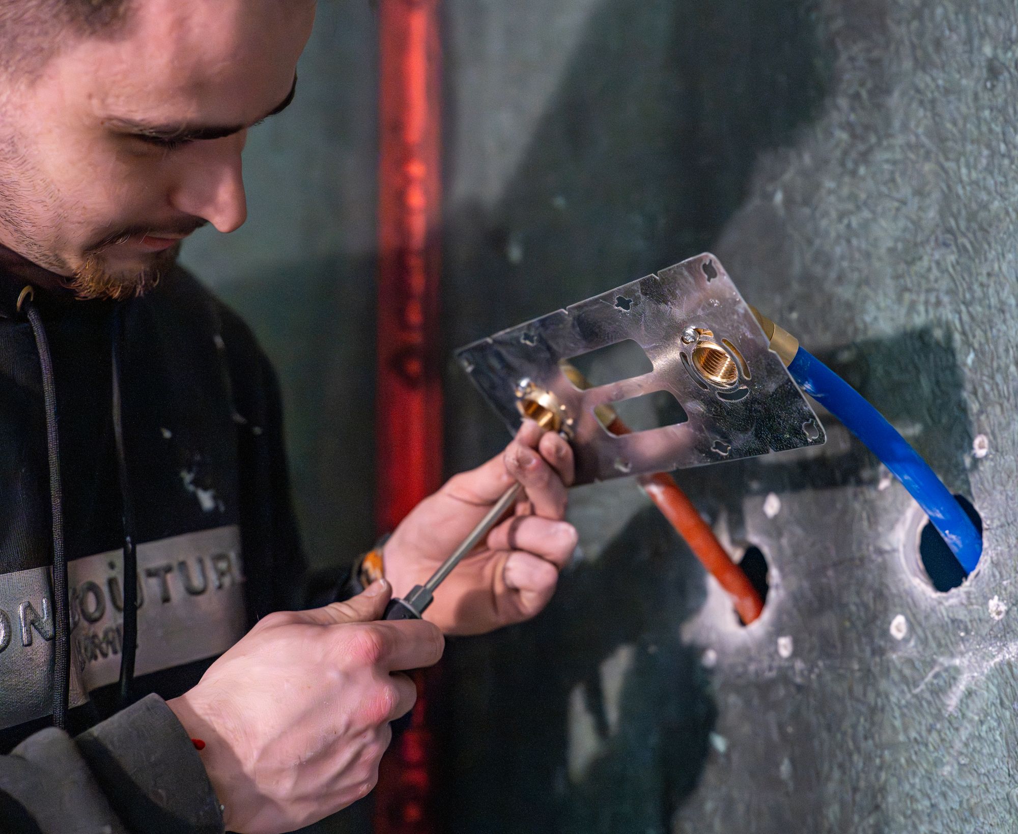 Plombier fixant une platine murale, Angel Carrelages