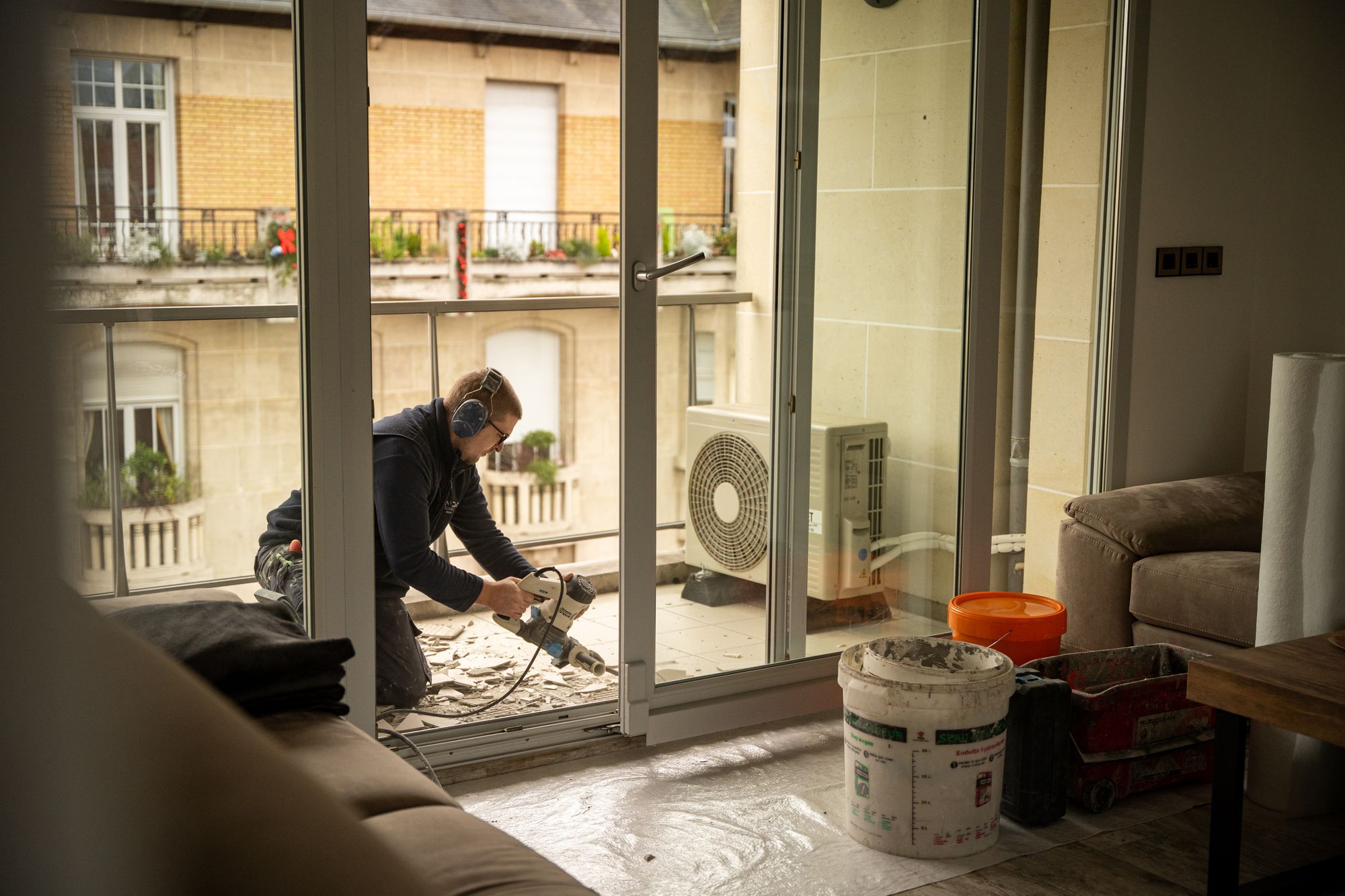 Carreleur au travail sur un chantier de baie vitrée, Angel Carrelages