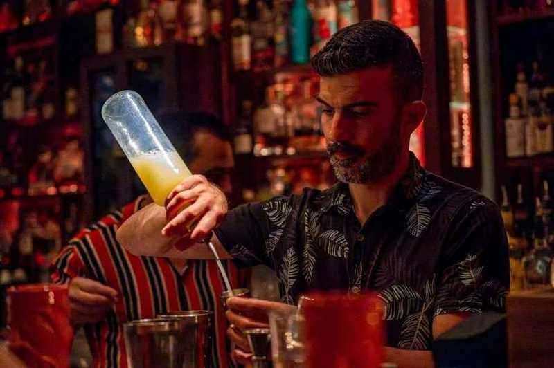 Bartender versant un cocktail rouge dans un shaker