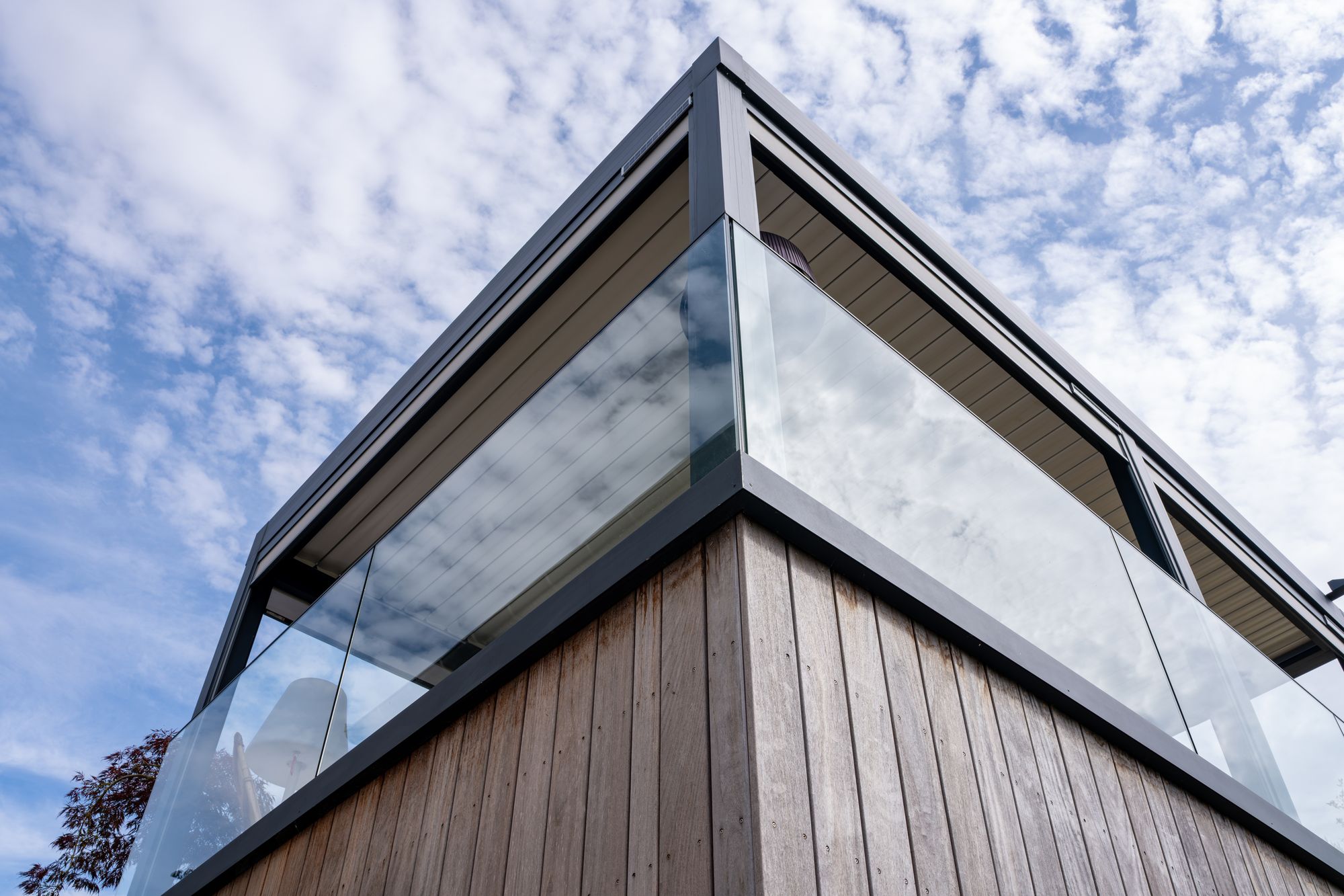 Angle de bâtiment bardé de bois avec garde-corps vitré, Frechin