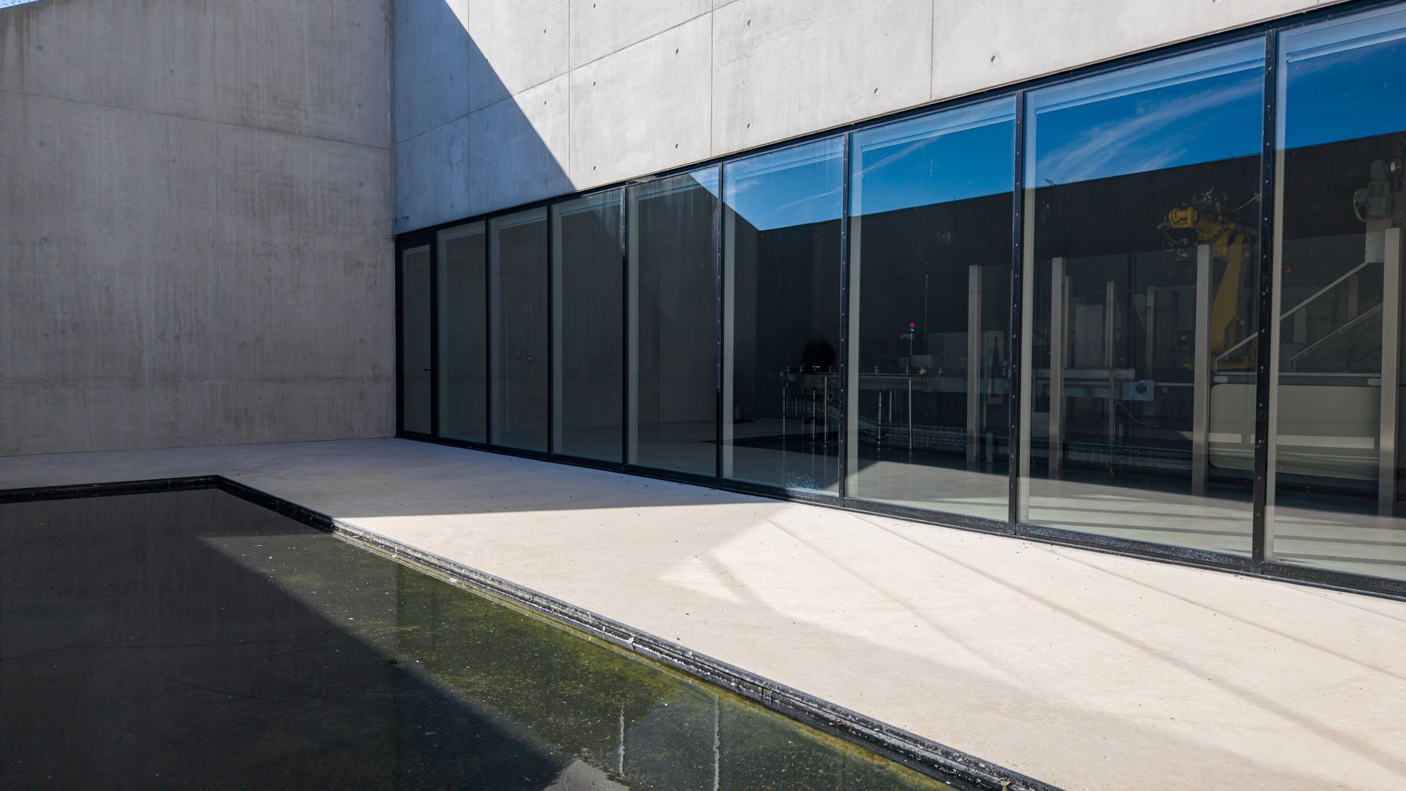 Façade vitrée en aluminium noir donnant sur un bassin d’eau, Frechin