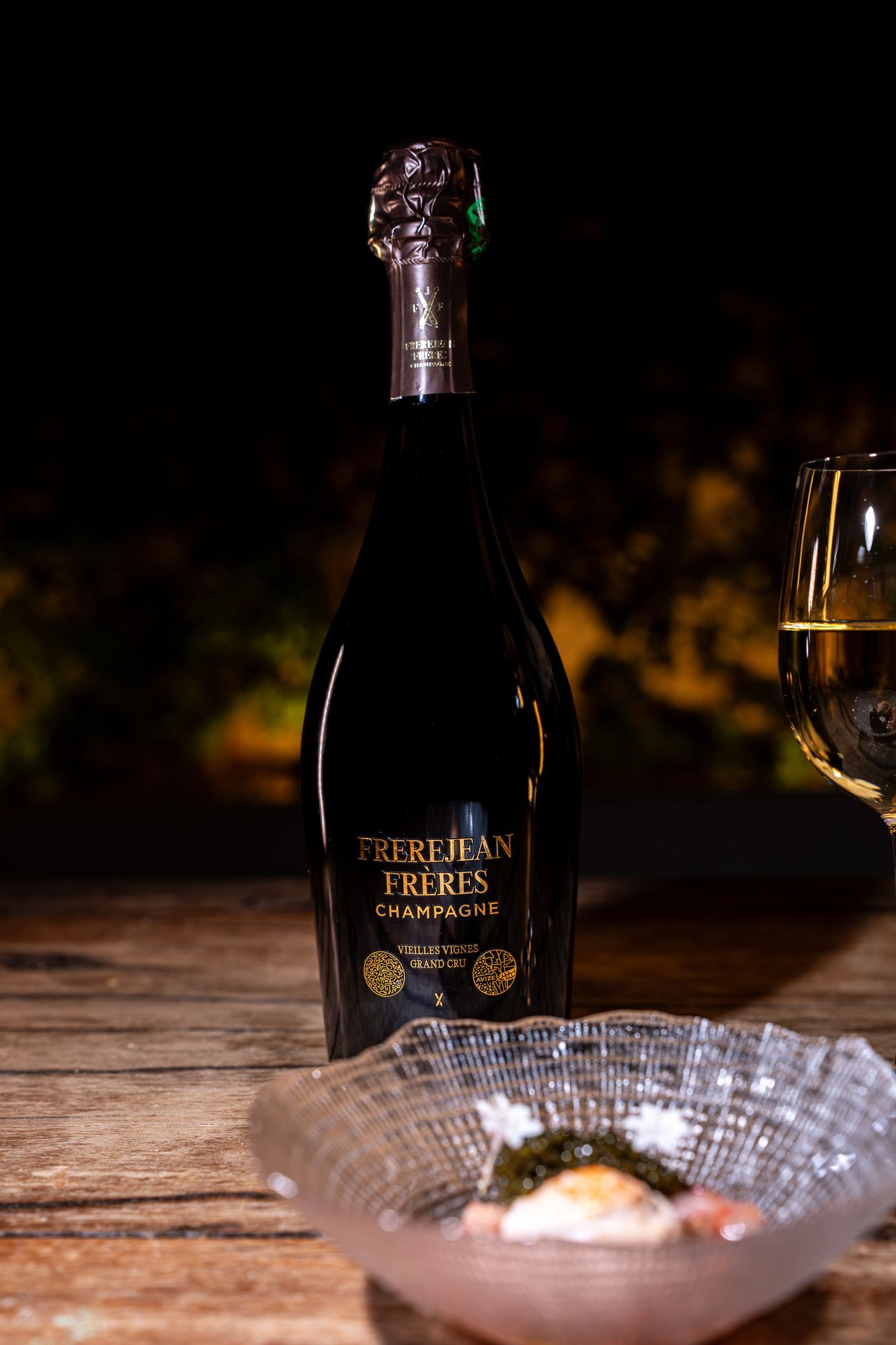 Bouteille Frerejean Frères Vieilles Vignes servie avec un plat sur une table en bois