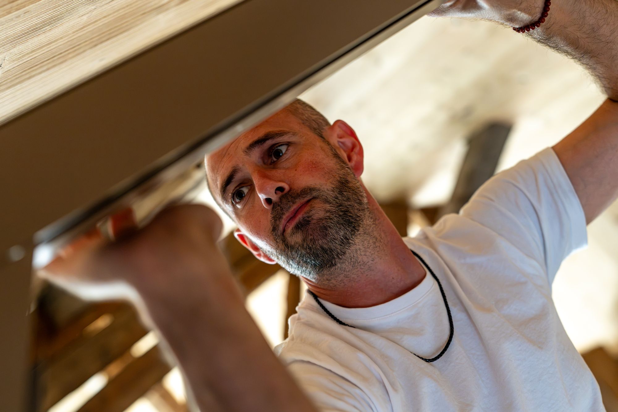 Menuisier ajustant un meuble sous une structure en bois, Menuiserie Janin