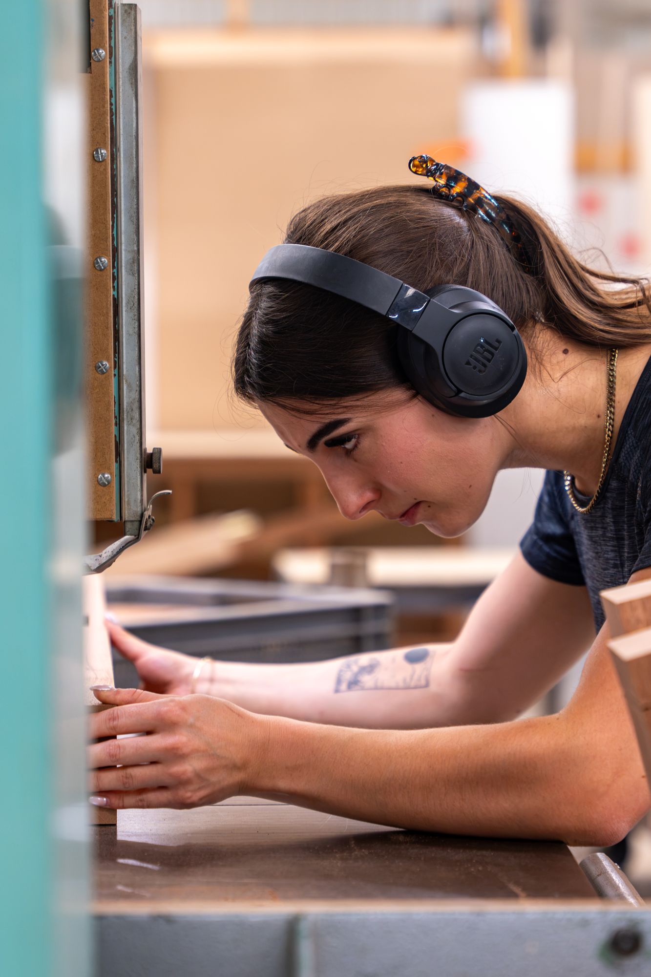 Artisane ajustant une pièce en atelier, casque audio sur les oreilles, Menuiserie Janin