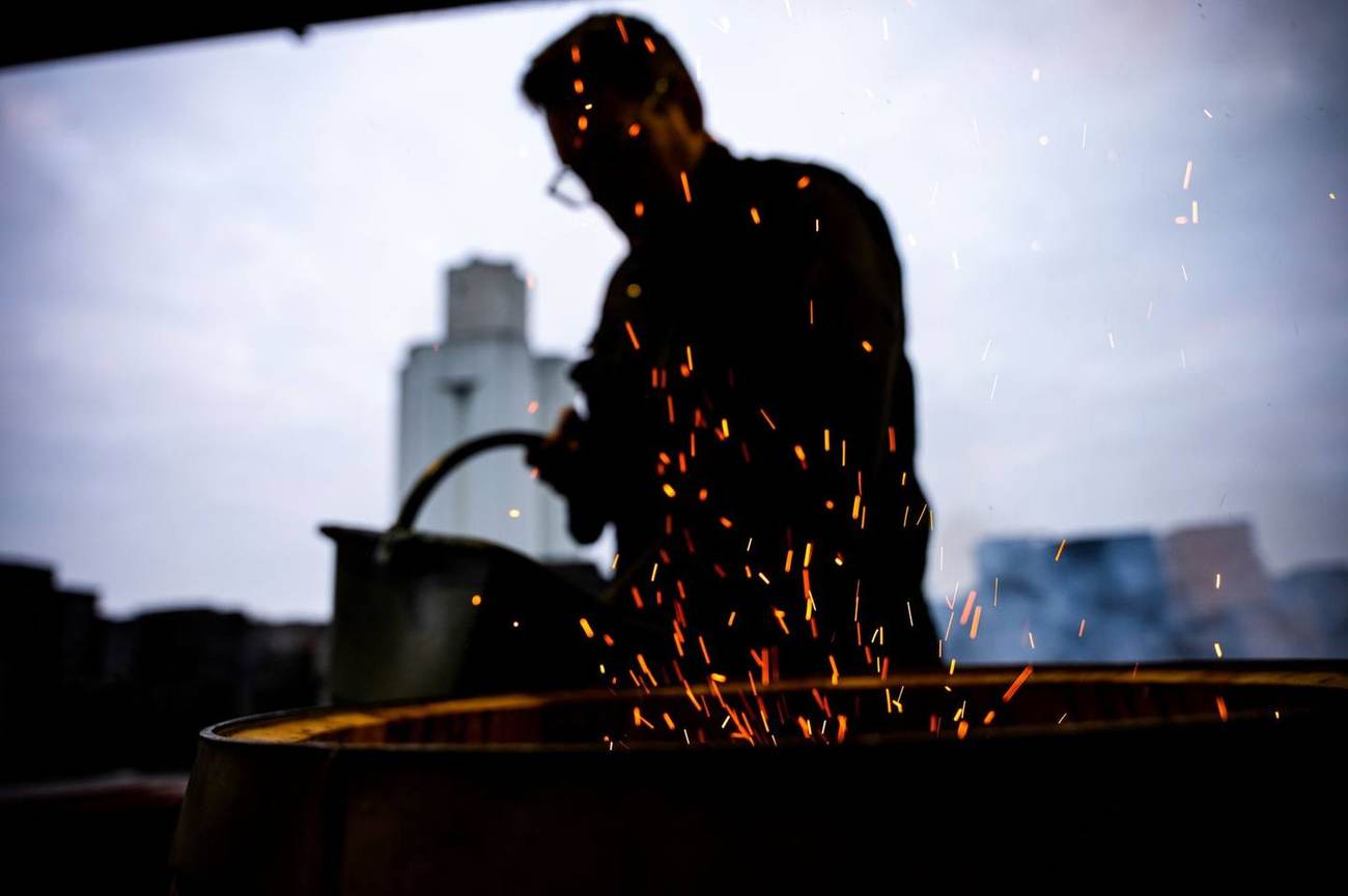 Artisan tonnelier au travail devant la flamme